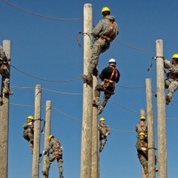 Arbeiten ist ein Gemeinschaftsprozess-Tag der Arbeit - Männer installieren auf Masten Stromleitungen